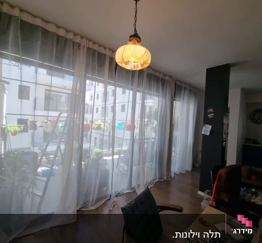 סולם מתכת ליד חלון עם וילון שקוף